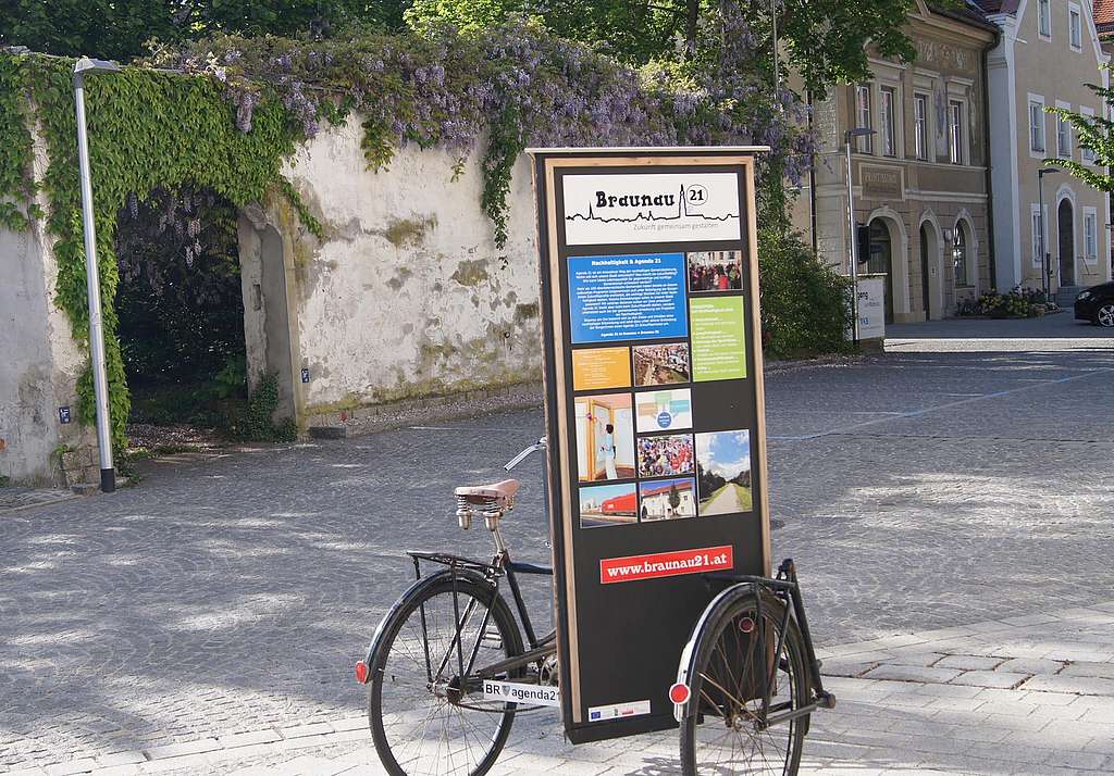 Ein Fahrrad mit Infotafeln steht auf einem Stadtplatz