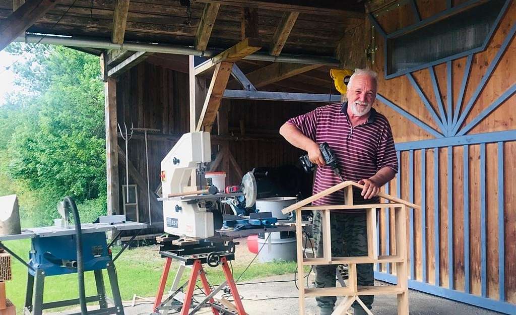 Älterer Mann mit Säge und Werkzeug, bastelt ein Insektenhotel