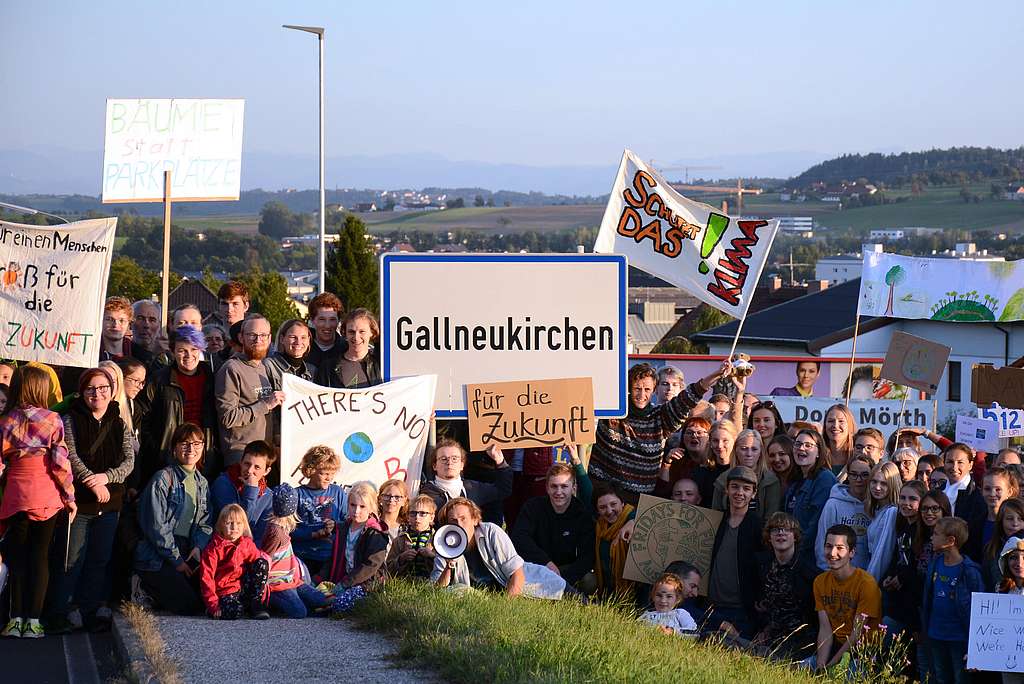 Klimaaktivisten versammeln sich mit Plakaten rund um die Ortstafel Gallneukirchen