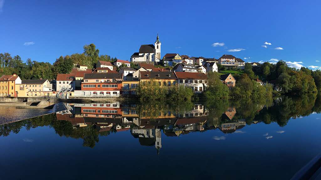 Ansicht des Ortes Steinbach an der Steyr, im Vordergrund ein Fluss, dahinter blauer Himmel