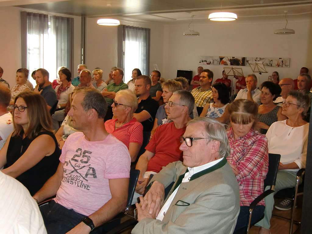 Ein gut gefüllter Gemeindesaal, Menschen hören einen Vortrag