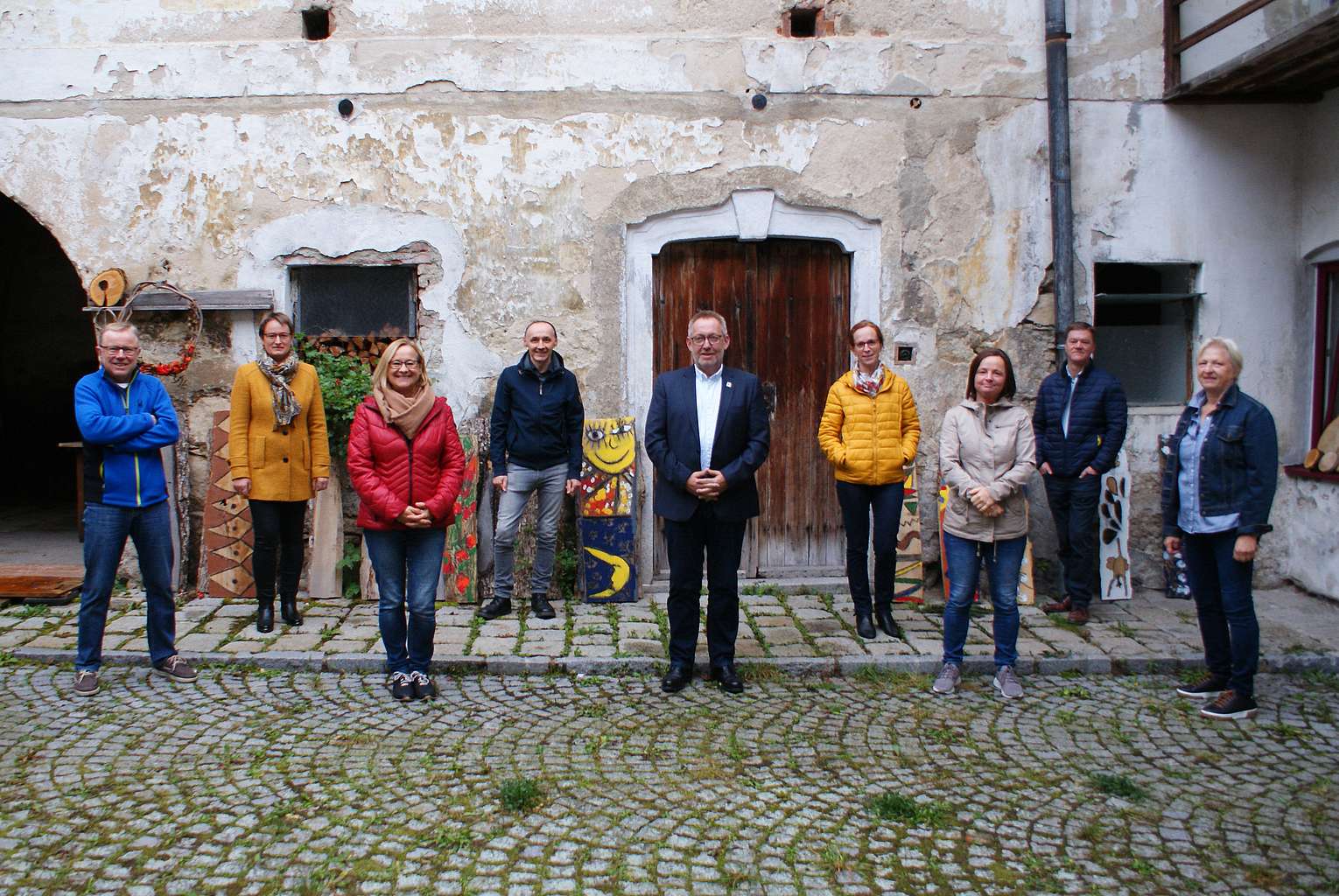Gruppenfoto einer Exkursionsgruppe, 10 Personen, vor altem Haus mit bröckelnder Fassade