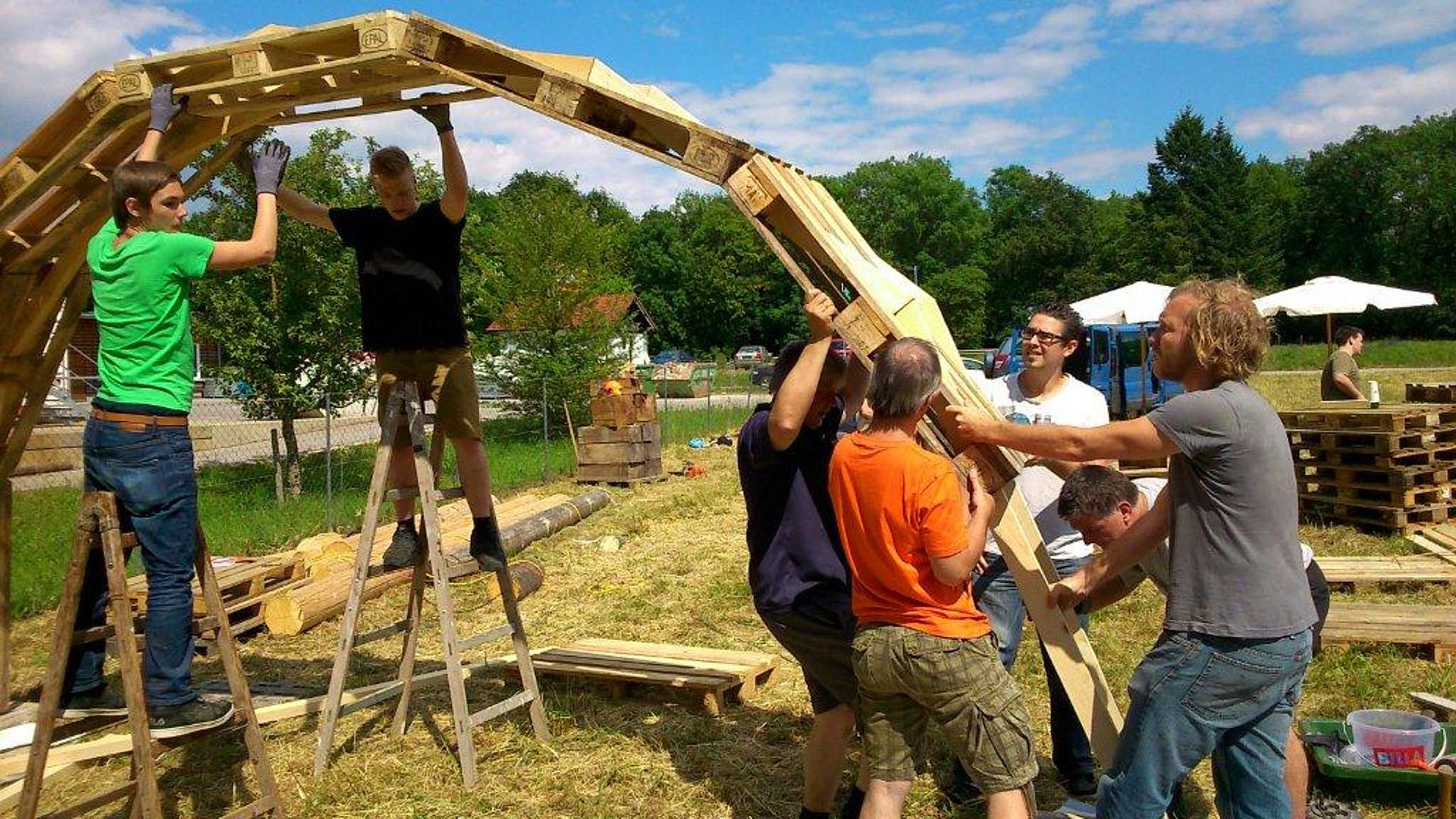 Sieben Personen bauen einen Pavillon aus Paletten